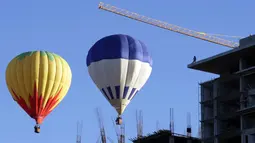 Pekerja bangunan gedung memperhatikan balon udara yang melitasinya Festival Balon Internasional ke-XV di Metropolitan Park di Leon, negara bagian Guanajuato, Meksiko (20/11). (AFP/STR)
