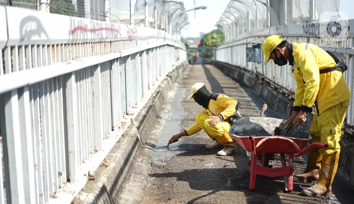 Petugas Bina Marga memerbaiki lantai Jembatan Penyeberangan Orang (JPO) yang berlubang di kawasan Tebet, Jakarta, Kamis (27/8/2020). Perbaikan dilakukan guna meningkatkan kenyamanan bagi pejalan kaki yang melintas. (Liputan6.com/Immanuel Antonius)