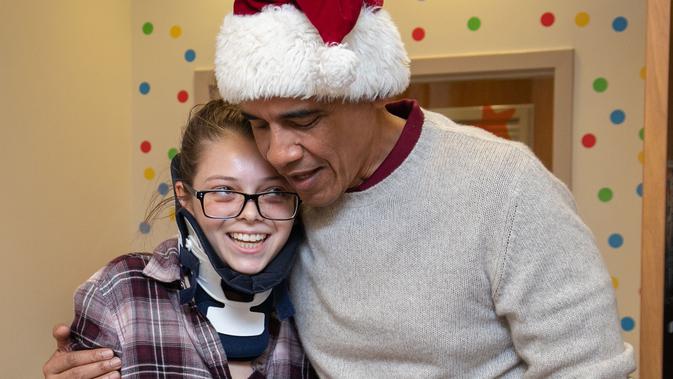 Mantan Presiden AS, Barack Obama memeluk seorang pasien anak di Children's National Medical Center , Washington, Rabu (19/12). Kedatangan Obama yang menyerupai sinterklas itu untuk membagikan hadiah kepada anak-anak di sana. (Chuck Kennedy / AFP)