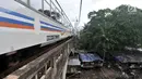 Kereta api melintas di atas bangunan liar yang berada di bantaran Kali Ciliwung, Jakarta, Kamis (12/4). Warga sekitar mengaku betah tinggal di bantaran kali meski rela kebanjiran di kala musim penghujan. (Merdeka.com/Iqbal Nugroho)