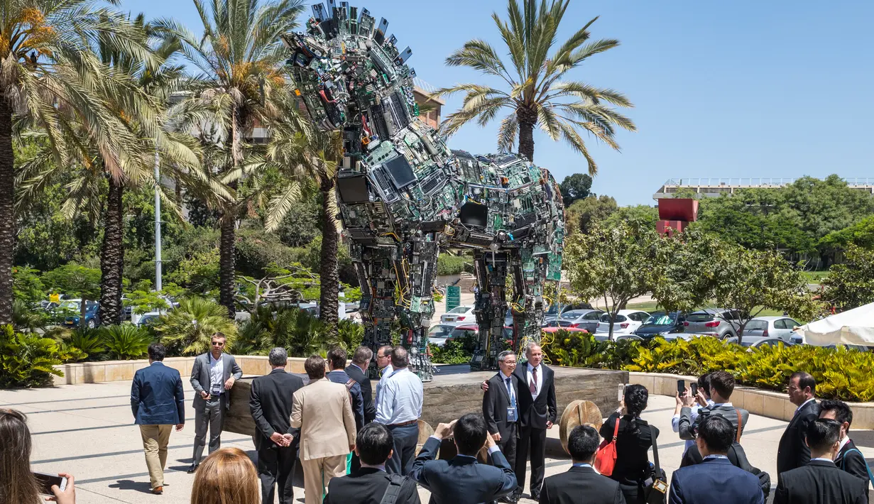 Pengunjung berfoto di replika patung kuda troya bernama "Cyber Horse" yang terbuat dari ribuan komputer dan komponen ponsel yang terinfeksi virus, di pintu masuk konferensi Cyber Week tahunan di Tel Aviv University, Israel, Senin (20/6). (Jack GUEZ/AFP)