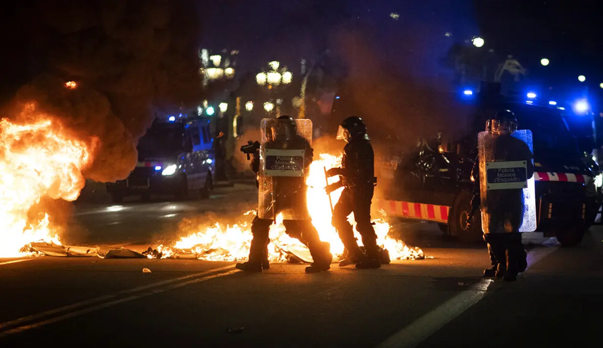 Polisi mengarahkan senjata ke demonstran saat bentrok dalam protes penangkapan rapper Pablo Hasel di Barcelona, Spanyol, Selasa (16/2/2021). Protes meletus di Spanyol usai polisi menangkap Pablo Hasel yang menolak dipenjara karena menghina kerajaan dan memuji terorisme. (AP Photo/Emilio Morenatti)