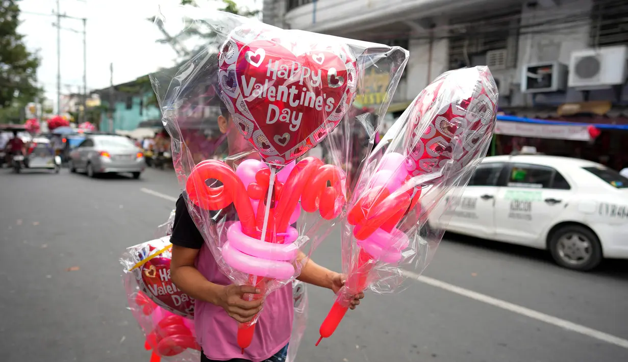 Seorang pria membawa balon berbentuk hati di pasar bunga di Manila, Filipina, Senin (13/2/2023). Harga bunga naik karena tingginya permintaan sehari sebelum Hari Valentine. (AP Photo/Aaron Favila)