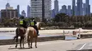 Polisi berpatroli dengan menunggang kuda di sepanjang St Kilda Esplanade di Melbourne (26/10/2020). Australia telah menghabiskan berbulan-bulan di bawah pembatasan yang berat setelah menjadi episentrum gelombang kedua negara itu. (AFP Photo/William West)