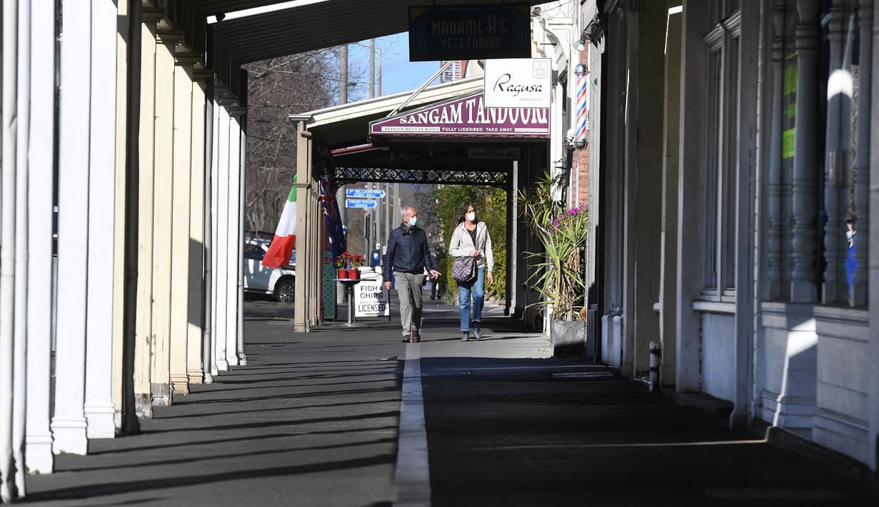 Orang-orang berjalan menyusuri jalur kafe yang biasanya ramai saat kota itu mengalami penguncian keenam saat memerangi wabah varian Delta dari coronavirus.di Melbourne (25/8/2021). (AFP/William West)