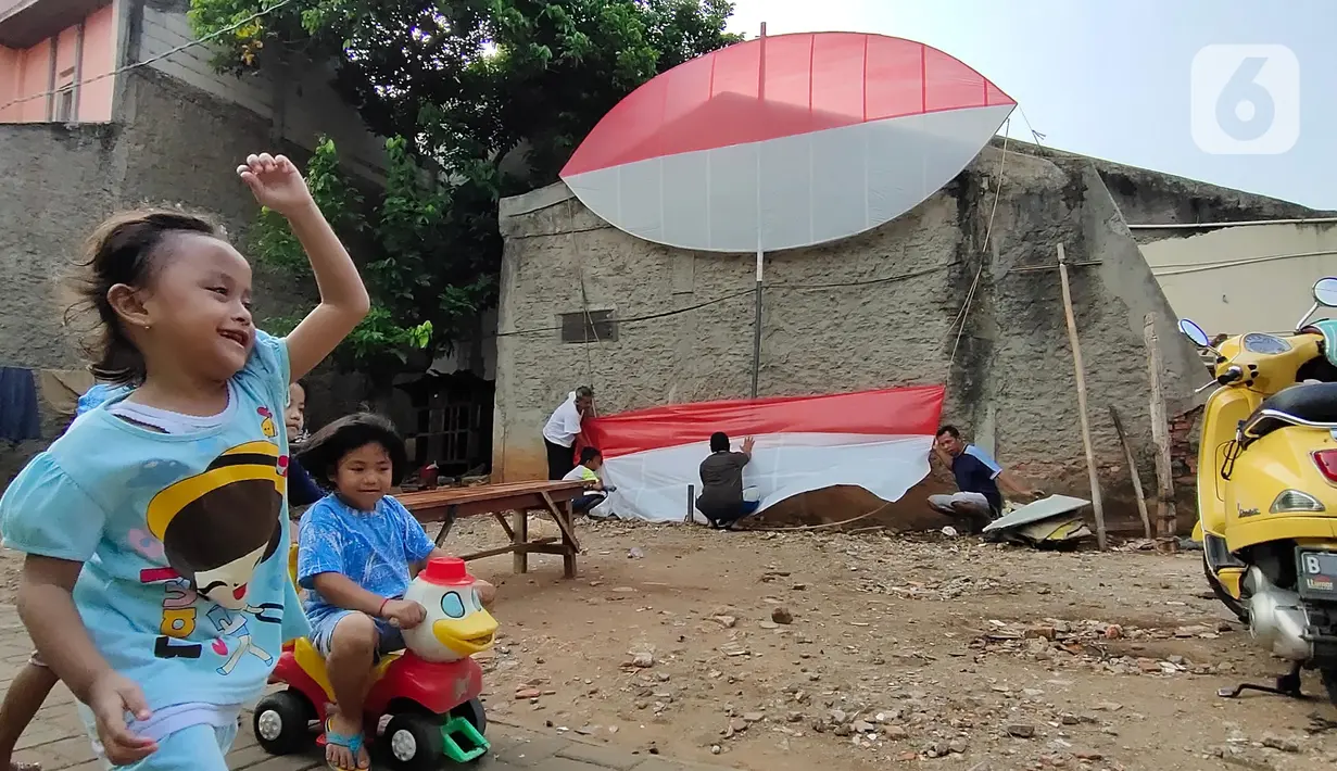 Anak-anak bermain saat warga membuat layang-layang merah putih setinggi enam meter di Kawasan Peninggilan, Tangerang, Senin (10/8/2020). Layang-layang merah putih tersebut dibuat untuk memeriahkan HUT Ke-75 Kemerdekaan Republik Indonesia. (Liputan6.com/Angga Yuniar)