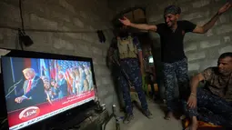 Seorang anggota pasukan Irak tertawa saat menonton siaran pidato kemenangan Donald Trump di Desa Arbid, Mosul (9/11). Perdana Menteri Irak Haider al-Abadi memberi selamat kepada Donald Trump yang terpilih menjadi Presiden AS. (AFP PHOTO/Ahmad Al-Rubaye)