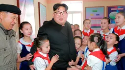 Ekspresi Kim Jong-un saat sejumlah anak memeluk  diri saat berkunjung ke Samjiyon (28/11). Puluhan anak sekolah histeris kegirangan saat bertemu dengan pemimpin negara mereka. (REUTERS/KCNA)