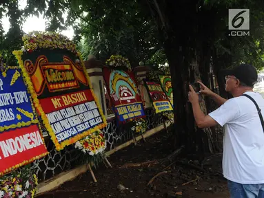 Warga mengambil gambar karangan bunga jelang Basuki Tjahaja Purnama atau Ahok bebas di Mako Brimob, Kelapa Dua Depok, Kamis (24/1). Dalam hitungan jam, Basuki Tjahaja Purnama atau Ahok akan segera menghirup udara bebas. (Liputan6.com/Herman Zakharia)