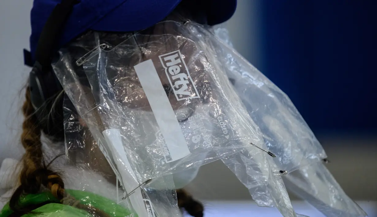 Penumpang mengenakan masker dan kantong makanan plastik sebagai tindakan pencegahan terhadap virus corona COVID-19 setelah mendarat di bandara internasional Hong Kong (19/3/2020). Covid-19 yang menginfeksi lebih dari 200.000 orang terus menimbulkan kekhawatiran. (AFP/Anthony Wallace)