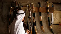 Seorang pengunjung melihat koleksi pedang yang dibuat oleh Mueen Abu Wadi di bengkel kerjanya di Kota Gaza, Palestina (14/11). Mueen Abu Wadi meneruskan pekerjaan ayah dan kakeknya menjadi pembuat pedang. (REUTERS/Suhaib Salem)