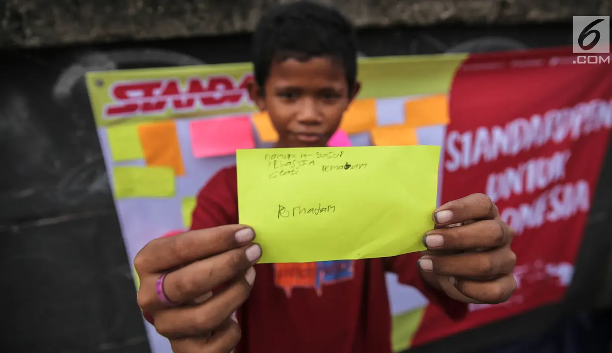 Seorang anak menunjukan tulisan cita-citanya  di jalur banjir kanal barat Tanah Abang, Jakarta, Senin (31/7). Selain itu kegiatan tersebut juga untuk menyambut bulan kemerdekaan RI. (Liputan6.com/Faizal Fanani)