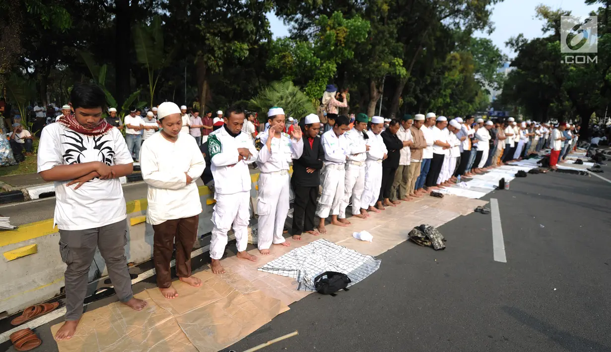 Massa pendukung pasangan capres-cawapres Prabowo Subianto dan Sandiaga Uno melakukan salat asar di Jalan Medan Merdeka Barat, Jakarta, Kamis (27/6/2019). Aksi tersebut dilakukan jelang putusan perselisihan hasil pemilihan umum (PHPU) Pilpres 2019 di Gedung MK. (merdeka.com/Arie Basuki)