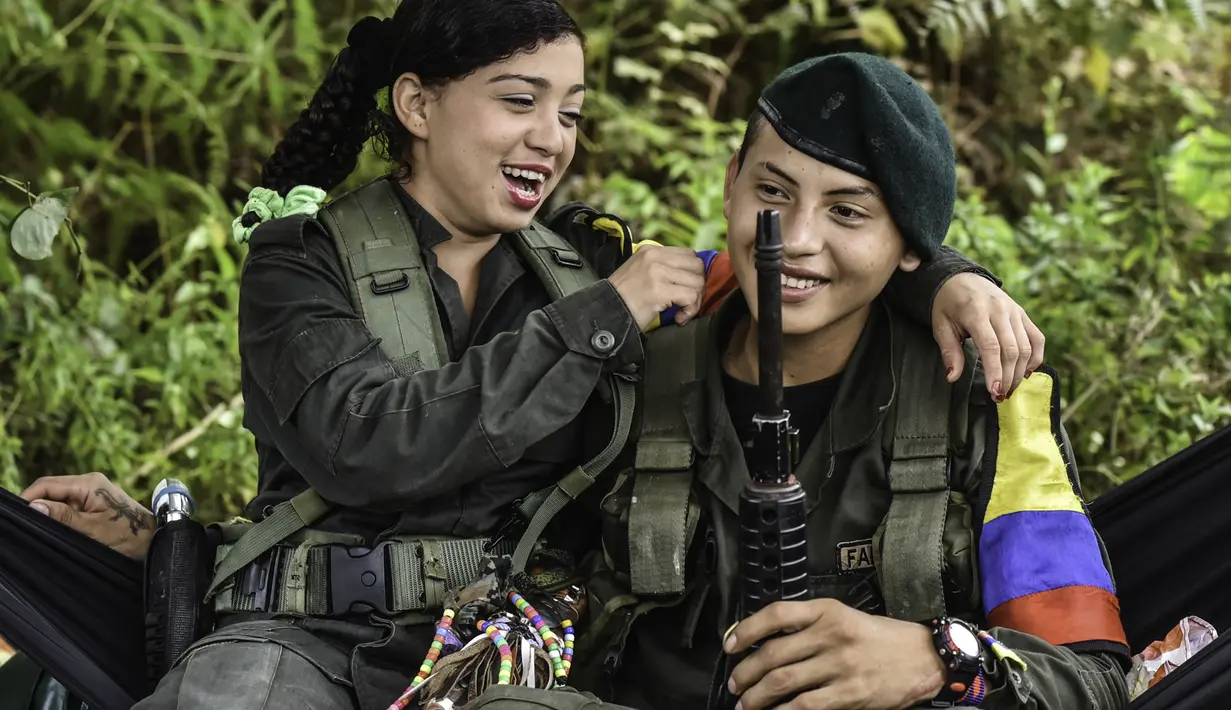 Seorang gerilyawati FARC sedang bercanda dengan kawannya di kamp Magdalena Medio, Kolombia (15/3/2016).  Gerilyawati FARC dikenal lebih sadis terhadap musuh daripada pasukan gerilyawan. (AFP Photo/Luis Acosta)