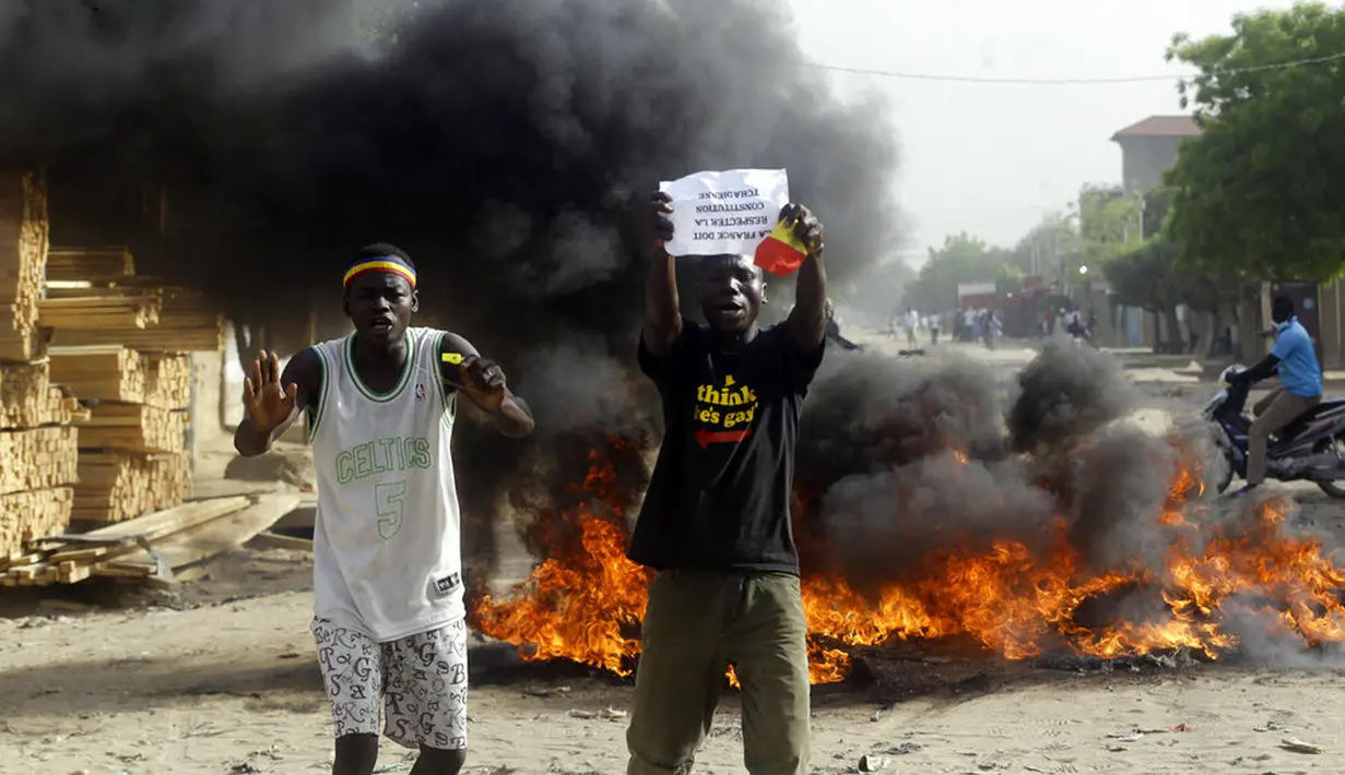 Dua pria melakukan protes di sebuah jalan di N'Djamena, Chad, Selasa (27/4/2021). Ribuan orang melakukan protes dan dua orang tewas dalam demonstrasi menentang aturan dewan militer transisi yang dipimpin putra Presiden Idriss Deby Itno yang terbunuh minggu lalu. (AP Photo/Sunday Alamba)