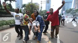 Mahasiswa menolong temannya yang terkapar saat aksi perayaan ekspresi identitas Papua di Jakarta, Selasa (1/12). Puluhan massa aksi diamankan dalam aksi tersebut sementara beberapa lainnya mengalami luka akibat bentrokan. (Liputan6.com/Immanuel Antonius)