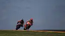 Pembalap Aprilia Racing, Maverick Vinales (kiri) dan pebalap Repsol Honda Marc Marquez memacu kecepatan sepeda motornya pada sesi latihan bebas kedua balapan MotoGP Aragon 2022 di sirkuit Motorland di Alcaniz, Spanyol, Jumat (16/9/2022). (PIERRE-PHILIPPE MARCOU / AFP)