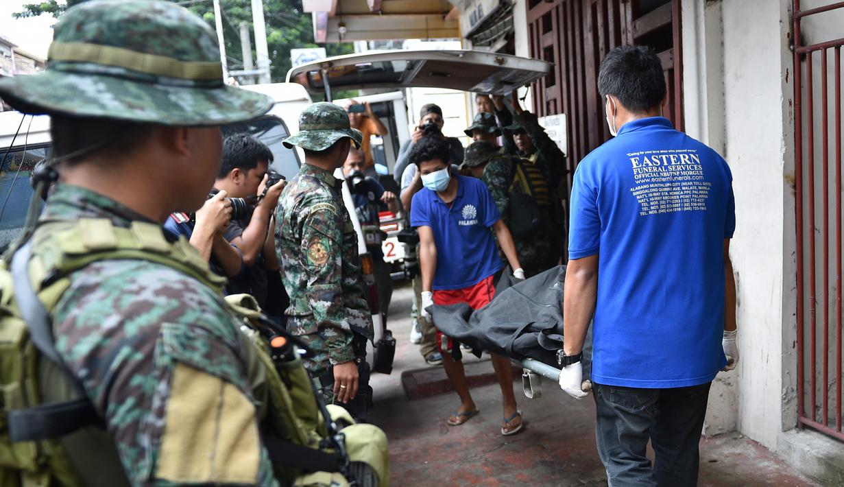 Personel polisi Filipina mengamati pekerja yang membawa jasad seorang napi yang tewas akibat kerusuhan di sebuah penjara di Filipina, Rabu (28/9). Selain menewaskan satu anggota geng narkoba, kerusuhan itu juga melukai tiga napi lainnya. (TED Aljibe/AFP)