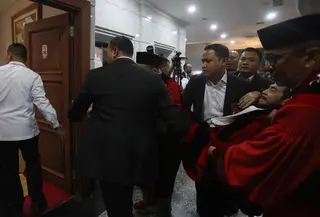 Anwar Usman kemudian dibopong menuju ruang tunggu Mahkamah Konstitusi untuk mendapatkan penanganan medis dari tim dokter. Tampak dalam foto, Anwar Usman dibopong ke ruang tunggu usai mengikuti prosesi wisuda purnabakti di Ruang Sidang Mahkamah Konstitusi (MK), Jakarta, Senin (13/4/2026). (Kapanlagi.com/Budy Santoso)