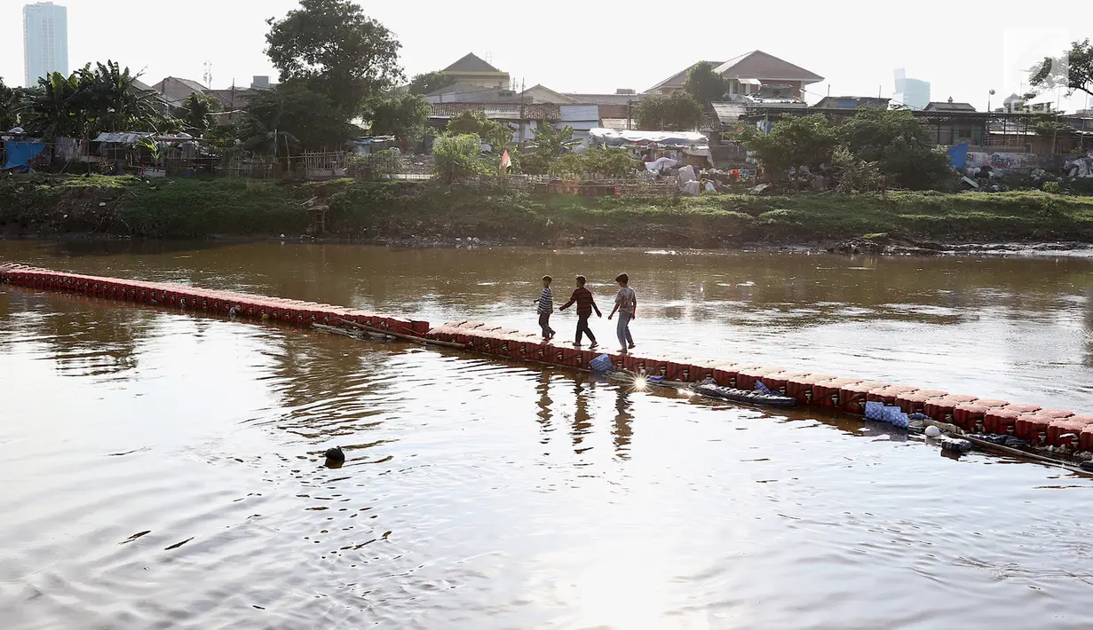 Anak-anak melintasi jembatan yang ada di Kanal Banjir Barat, Jakarta, Jumat (23/3). Selain mahalnya sewa kolam renang, berenang Kanal Banjir Barat dipilih anak-anak tersebut karena minimnya lahan bermain. (Liputan6.com/Immanuel Antonius)