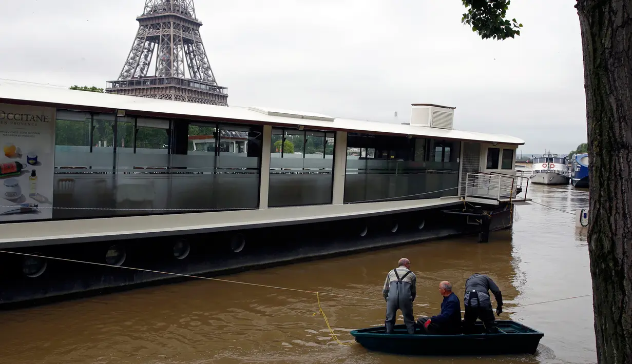 Warga berada di perahu di sungai Seine di dekat menara Eiffel, Paris, Prancis setelah hampir setiap hari hujan lebat menguyur negeri ini, (3/6). Banjir yang merendam sebagian wilayah Prancis Sejauh ini sudah dua orang tewas. (REUTERS/Pascal Rossignol)