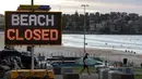 Tanda menunjukkan bahwa pantai ditutup ketika peselancar tiba pada pukul 7 pagi  di Sydney, Selasa, (28/4/2020).  (AP Photo/Rick Rycroft)