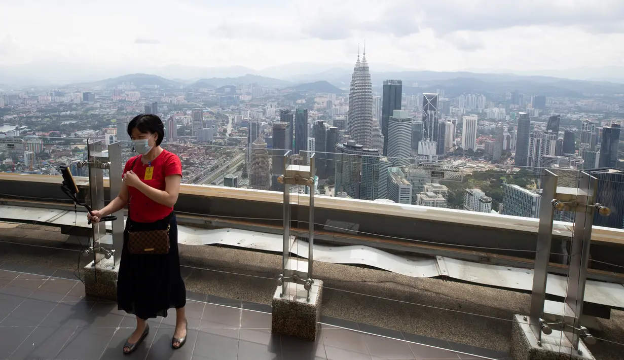 Seorang turis dengan mengenakan masker berswafoto saat mengunjungi dek obseravsi di Menara Kuala Lumpur di Kuala Lumpur, Rabu (1/7/2020). Malaysia memasuki pelonggaran Perintah Kontrol Gerakan (MCO) setelah tiga bulan pembatasan karena virus corona Covid-19. (AP Photo/Vincent Thian)
