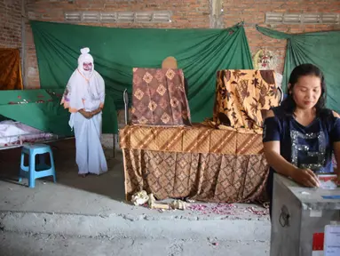 Warga memasukkan surat suara setelah mencoblos pada Pilkada Serentak 2018 di TPS 7 Randusari, Kota Semarang, Rabu ( 27 /6). Di TPS tersebut, para petugas berkostum ala hantu seperti pocong, kuntilanak, genderuwo dan sejenisnya. (Liputan6.com/Gholib)