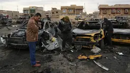 Sejumlah orang melihat-lihat di lokasi terjadinya ledakan bom mobil di permukiman al-Bayaa, Irak, Kamis (16/2). Pihak keamanan dan sumber medis mengatakan sedikitnya 48 orang tewas dan melukai 55. (AP Photo/ Karim Kadim) 