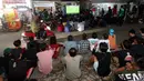 Warga duduk di pinggir jalan saat nobar pertandingan Timnas Indonesia U-23 vs Uzbekistan di kampung Sampora, Cisauk, Tangerang, Selasa (29/4/2024). (Bola.com/M Iqbal Ichsan)