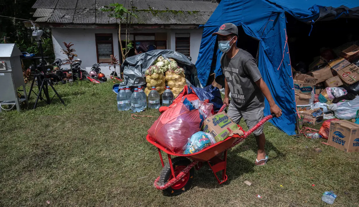Seorang pengungsi letusan gunung Semeru mengumpulkan jatah makanan mereka di tempat penampungan sementara di desa Sumber Wuluh di Lumajang, Jawa Timur, Senin (6/12/2021). Tim SAR Gabungan masih terus melakukan proses pencarian warga yang hilang. (Juni Kriswanto/AFP)