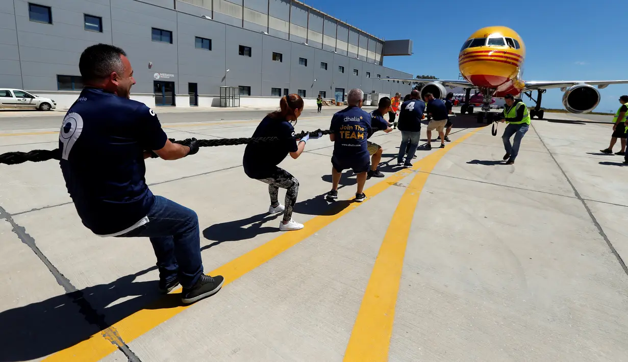 Anggota tim sekuat-tenaga untuk menarik pesawat DHL Boeing 757 sejauh 20 meter di Safi Aviation Park, Malta pada 1 Mei 2019. Kegiatan tarik pesawat tersebut merupakan rangkaian dalam rangka untuk penggalangan dana amal. (REUTERS/Darrin Zammit Lupi)