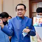 PM Thailand, Prayut Chan-O-Cha menyemprotkan pembersih tangan ke wartawan untuk menghindari pertanyaan perombakan kabinet selama konferensi pers di Bangkok, Selasa (9/3/2021). Sebelum menyemprot, Prayuth mengatakan kepada wartawan untuk mengurus urusan mereka sendiri. (HO/ROYAL THAI GOVERNMENT/AFP)