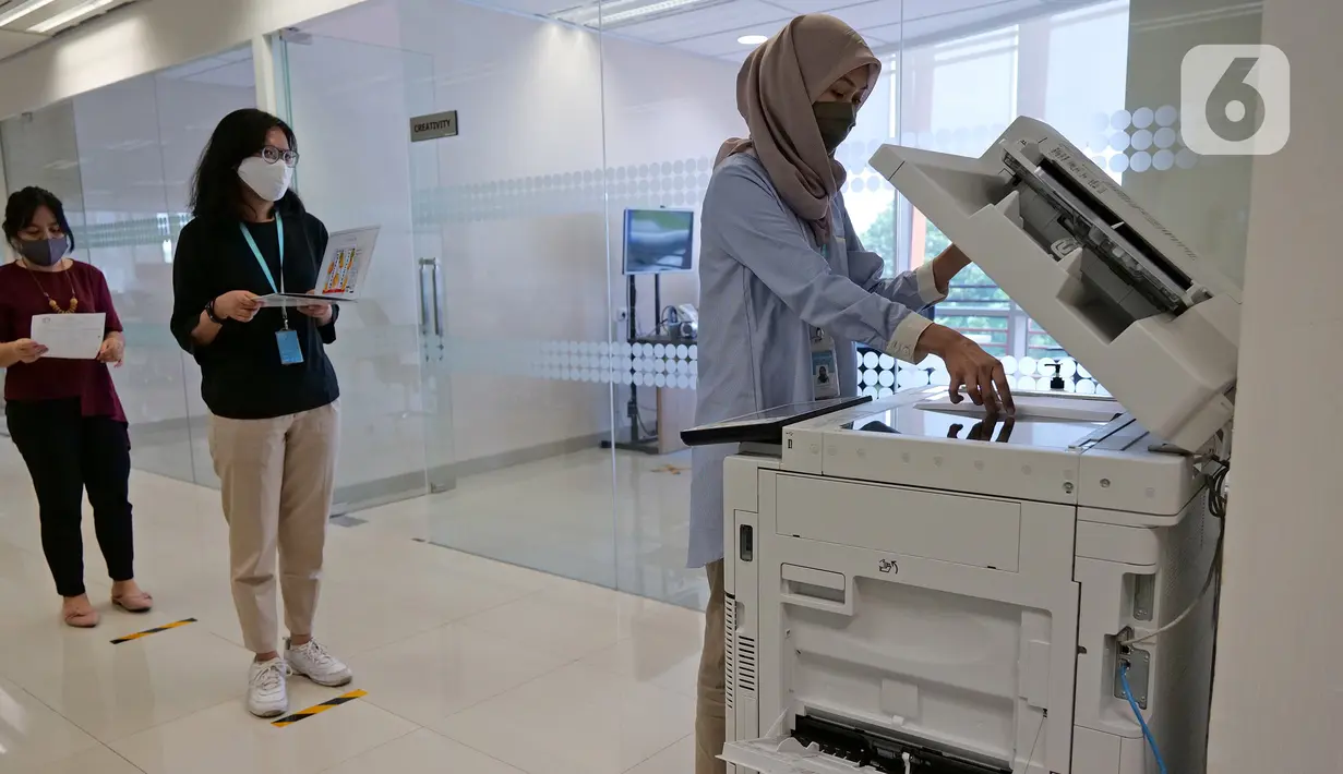 Karyawan menjaga jarak saat mengantre untuk fotokopi dokumen di Suntory Garuda, Jakarta, Senin (8/8/2020). Perusahaan tersebut menerapkan protokol kesehatan saat hari pertama kerja di masa PSBB transisi yang diterapkan oleh Pemprov DKI Jakarta. (Liputan6.com/Herman Zakharia)
