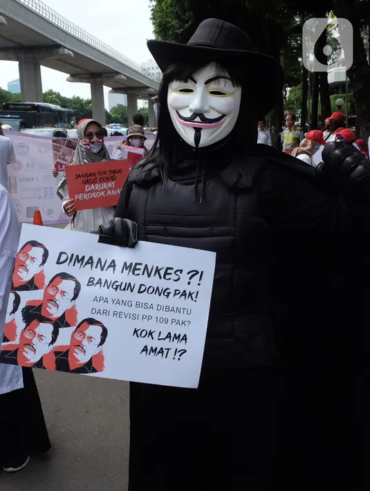 Massa Aliansi Koalisi Masyarakat Peduli Kesehatan (KOMPAK) mengenakan kostum Anonymous saat menggelar aksi di depan Kementerian Kesehatan, Jakarta, Kamis (26/11/2020). (Liputan6.com/Herman Zakharia)