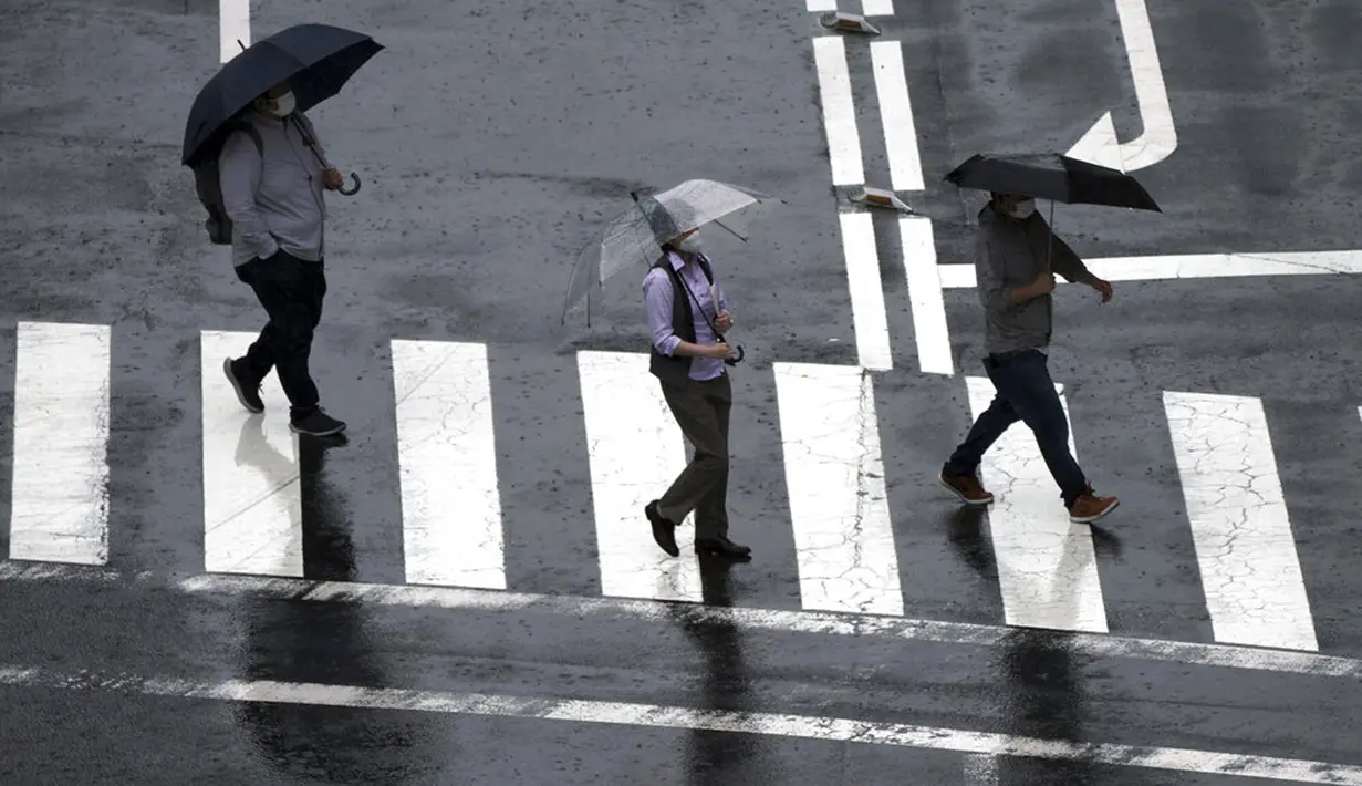 Orang-orang berjalan di tengah hujan saat Topan Mindulle di Tokyo, Jepang, Jumat (1/10/2021). Topan Mindulle sedang bergerak di lepas pantai Jepang. (AP Photo/Eugene Hoshiko)