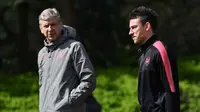 Pelatih Arsenal, Arsene Wenger (kiri) berbincang dengan Laurent Koscielny saat latihan di London Colney Arsenal, Inggris (25/4). Arsenal akan menghadapi wakil Spanyol, Atletico Madrid pada leg pertama babak semifinal Liga Europa. (AFP Photo/Ben Stansall)