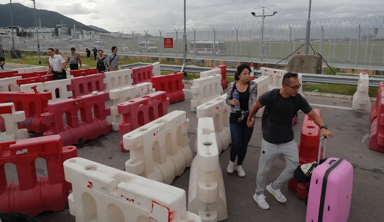Calon penumpang pesawat berjalan menuju Bandara Internasional Hong Kong melewati barikade yang dibuat oleh demonstran (1/9/2019). (AP Photo/Kin Cheung)