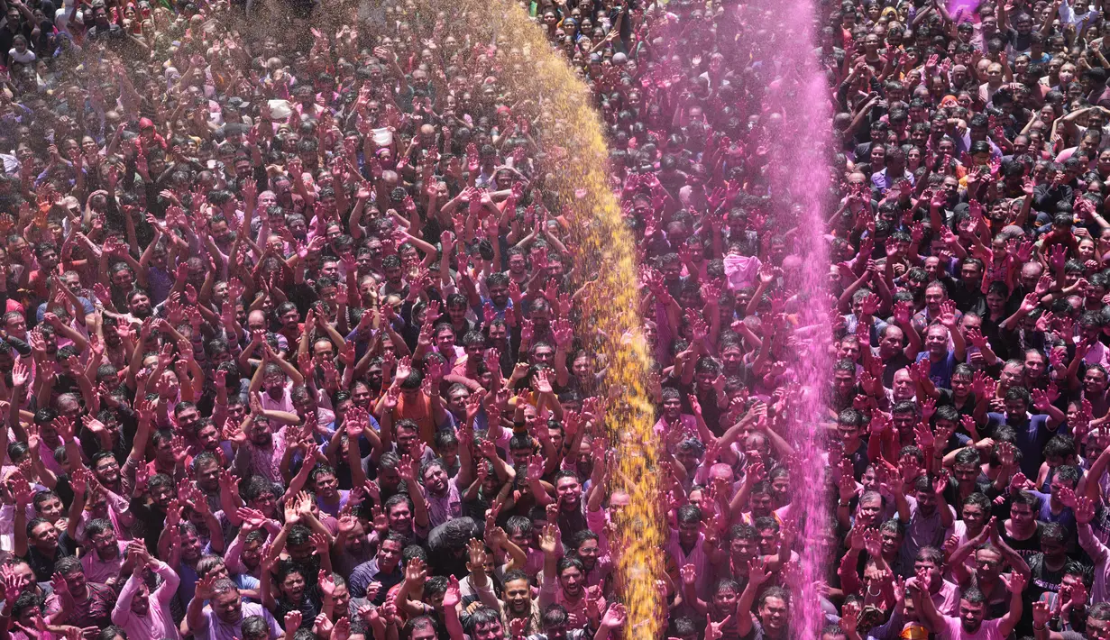 Umat Hindu bersorak saat bubuk berwarna dan air disemprotkan selama perayaan Festival Holi di kuil Kalupur Swaminarayan di Ahmedabad, India (18/3/2022).  Holi, festival warna Hindu, juga menandai datangnya musim semi. (AP Photo/Ajit Solanki)