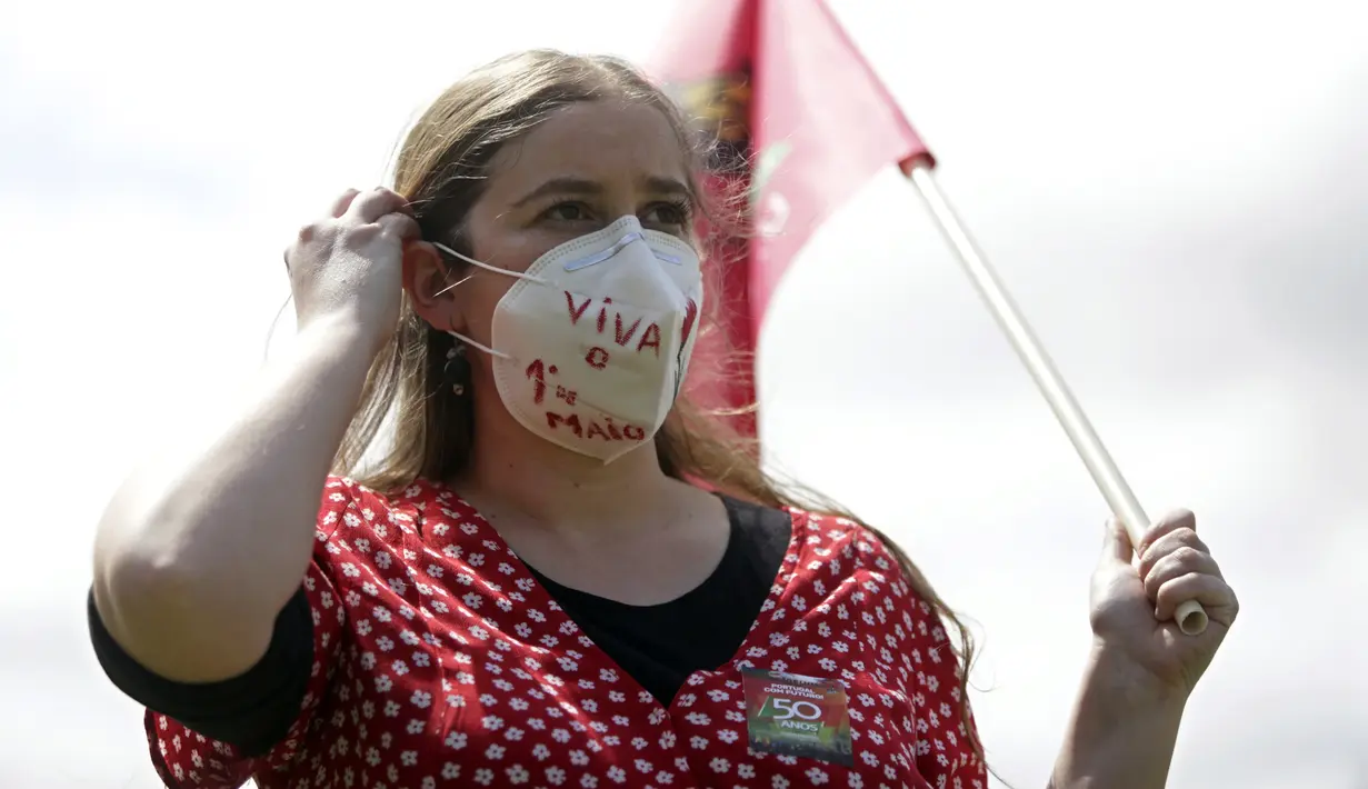 Delegasi serikat pekerja mengenakan masker sambil membawa bendera saat memperingati Hari Buruh di tengah pandemi COVID-19 di Lisbon, Portugal, Jumat (1/5/2020). Aksi ini sudah mendapat persetujuan Kementerian Kesehatan dan Dalam Negeri Portugal. (AP Photo/Armando Franca)