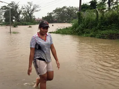 Seorang wanita berjalan melewati genangan banjir yang melanda Ba, wilayah barat Fiji, Rabu (6/4). Otoritas Fiji memerintahkan warganya untuk tetap berada di dalam ruangan seiring semakin mendekatnya siklon Tropis Zena. (NAZIAH ALI/MAI LIFE MAGAZINE /AFP)