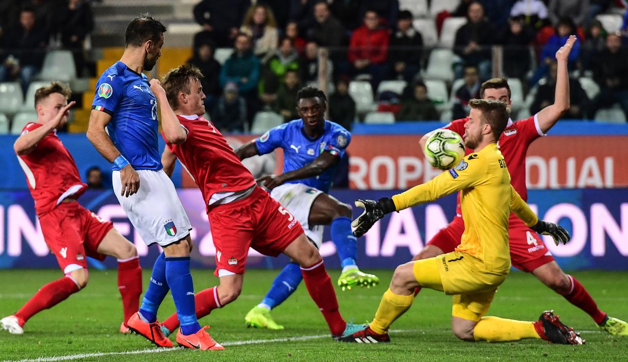 Kiper Liechtenstein, Benjamin Buchel, berusaha menghalau bola tendangan striker Italia, Moise Kean, pada laga Kualifikasi Piala Eropa 2020 di Stadion Ennio-Tardini, Selasa (26/3). Italia menang 6-0 atas Liechtenstein. (AFP/Miguel Medina)