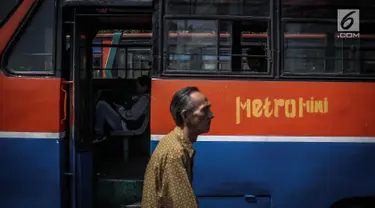 Seorang pria melintas diantara Metromini di Terminal Blok M, Jakarta, Rabu (26/7). Dinas Perhubungan (Dishub) DKI Jakarta akan merevitalisasi 700 unit metromini menjadi Minitrans. (Liputan6.com/Faizal Fanani)