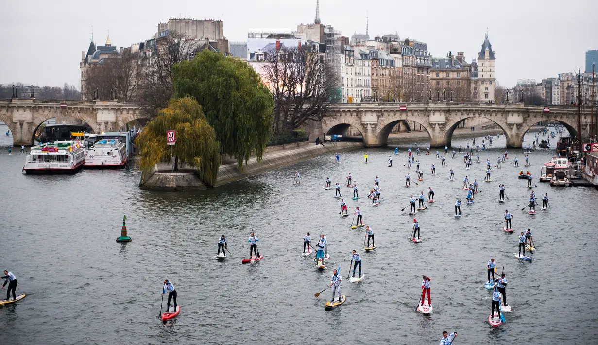 Peserta mendayung melewati aliran sunga- sungai selama perlombaan dayung dan perahu di Sungai Seine di Paris, Perancis, Minggu, (2/12). Acara ini diikuti oleh ribuan peserta dari berbagai kota di Paris. (AFP)