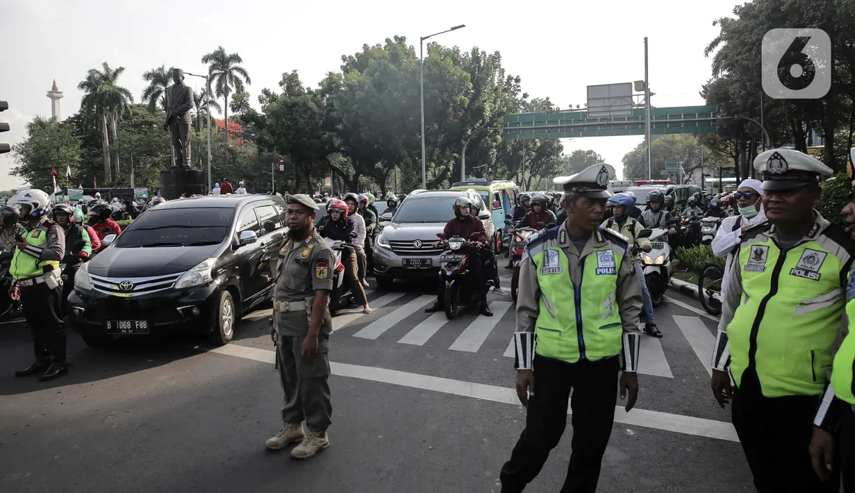 Polisi mengatur lalu lintas saat kendaraan terjebak kemacetan di kawasan Jalan Thamrin dan Merdeka Barat, Jakarta, Senin (2/12/2019). Sejumlah ruas jalan di Jakarta mengalami kemacetan parah akibat aksi reuni 212 di kawasan Monas. (Liputan6.com/Faizal Fanani)