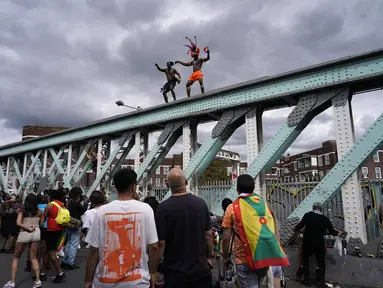 Orang-orang yang bersuka ria menari di atas jembatan kereta api selama Karnaval Notting Hill tahunan di London barat, Senin (29/8/2022). Karnaval yang kembali ke jalanan untuk pertama kalinya dalam dua tahun, setelah digagalkan oleh pandemi, adalah salah satu perayaan festival terbesar dari jenisnya di Eropa. (AP Photo/Alberto Pezzali)