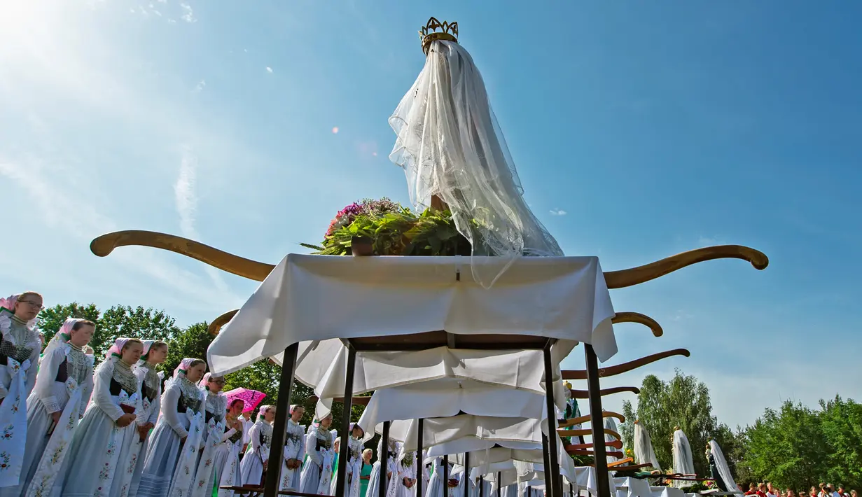 Sejumlah wanita berpakaian tradisional Sorbs berdiri di samping patung Bunda Maria selama prosesi ritual Whit Monday di Rosenthal, Jerman, Senin (10/6/2019). Para wanita muda membawa patung Bunda Maria ke sebuah lapangan untuk melangsungkan misa terbuka. (AP Photo/Jens Meyer)