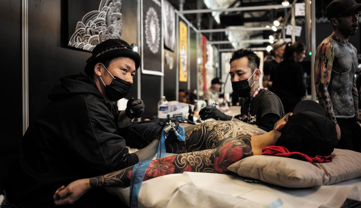 Seorang pria terbaring saat proses pembuatan tato di acara Paris Tattoo Convention di Grand Halle de la Villette, Paris, Prancis, Jumat (9/3). Paris Tattoo Convention berlangsung dari tanggal 9 sampai 11 Maret. (Philippe LOPEZ/AFP)