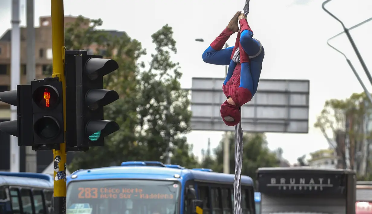 Seorang pria Kolombia bernama Jahn Fredy Duque bergelantungan layaknya superhero Spiderman di jalanan Bogota, Kolombia, Senin (24/4). Duque mencari nafkah dengan melakukan atraksi layaknya Spiderman. (AFP Photo/RAUL ARBOLEDA)