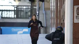 Seorang karyawan yang memakai celemek berlari keluar dari Kafe Lindt, Martin Place, Sydney, Senin (15/12/2014). (REUTERS/Jason Reed)